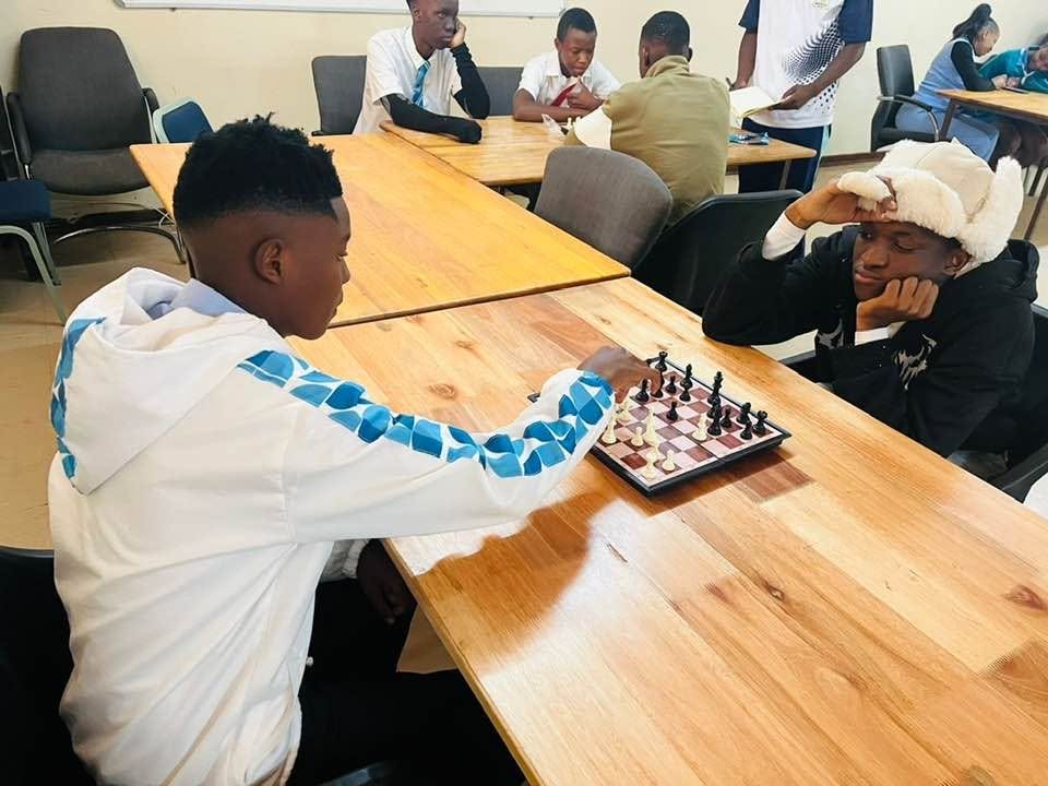 Advanced College learners playing chess at a table